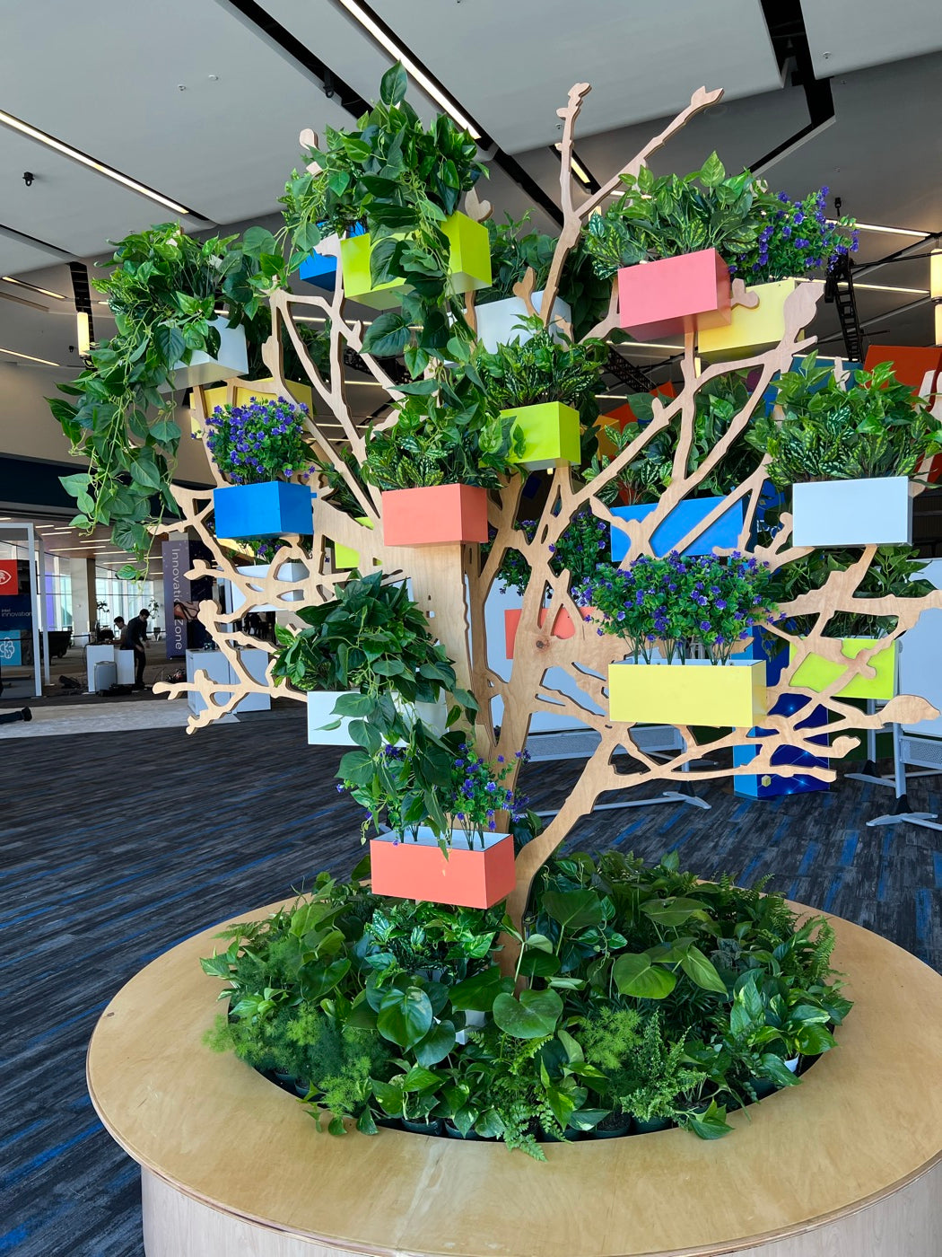 Sculptural tree canopy with colorful planter boxes anchoring an event floor