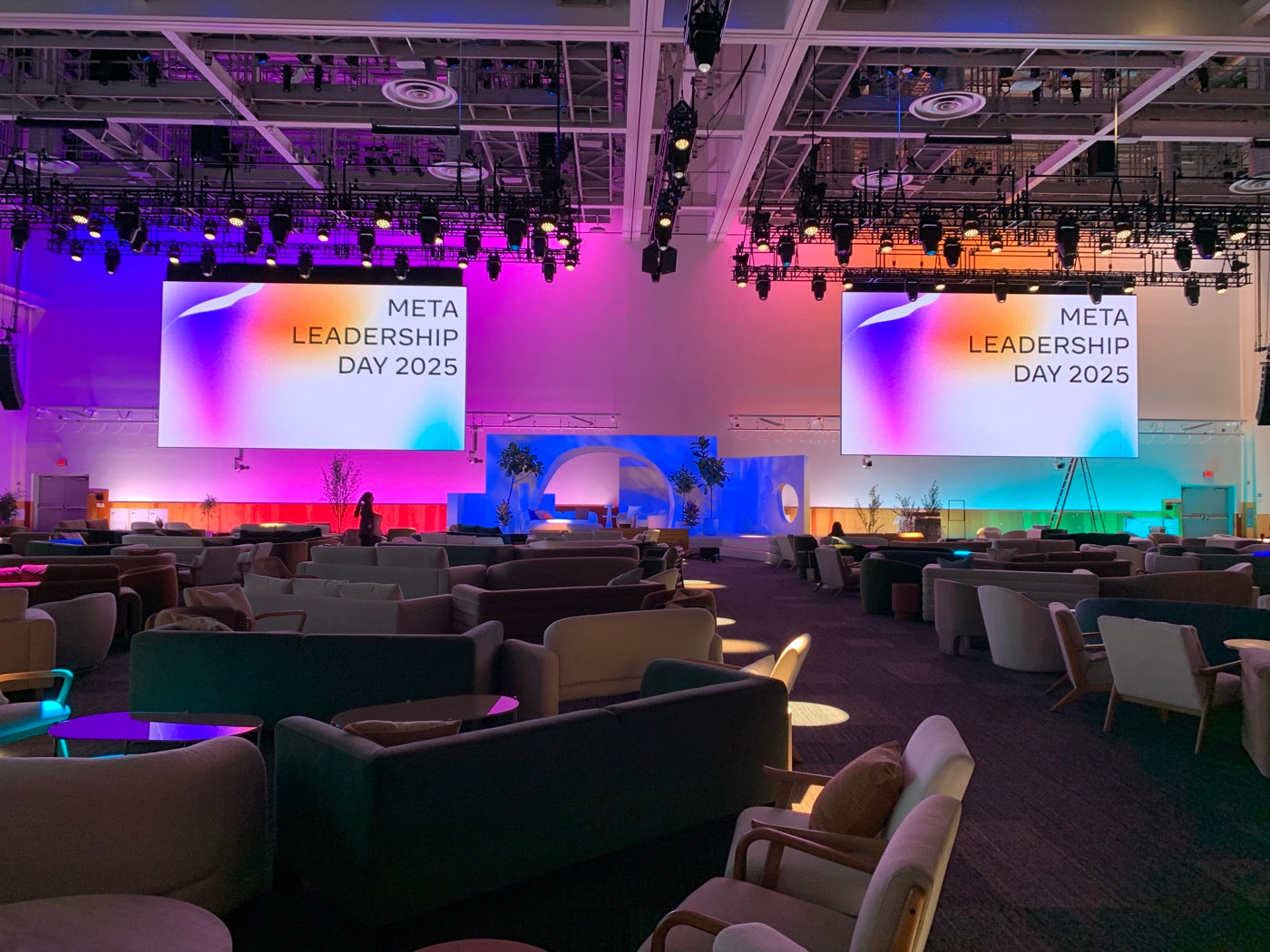 Plants framing a colorful full-floor corporate stage and lounge build