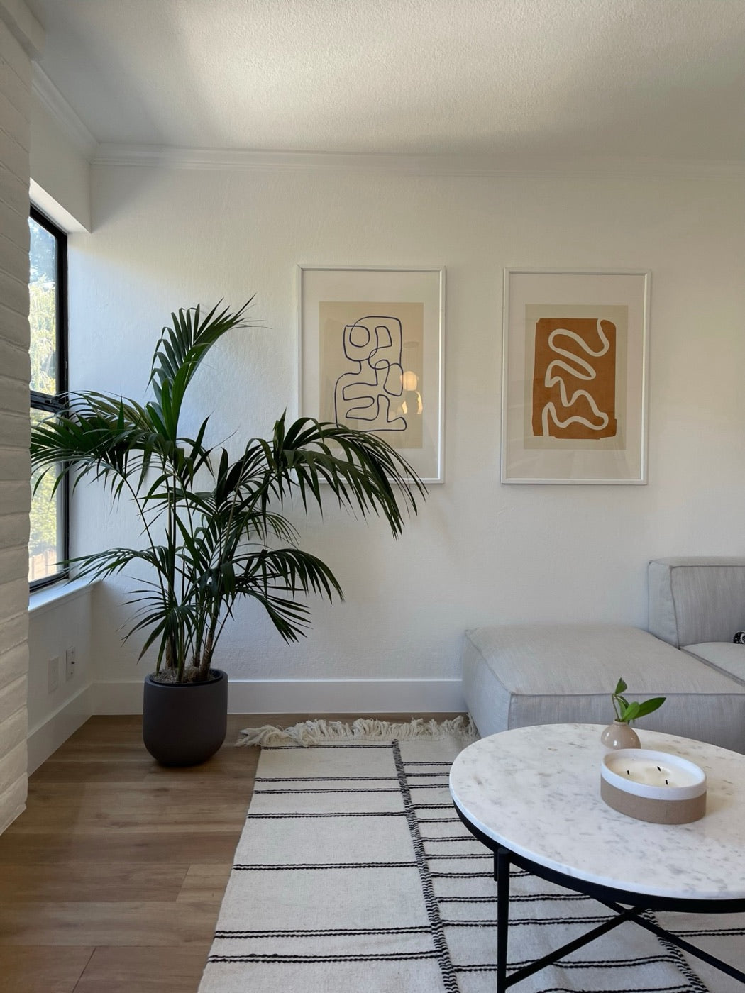 Kentia palm in a dark planter finishing a staged living room with framed art and a marble coffee table